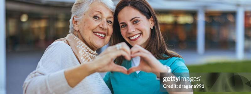 two women making a shape of a heart with their hands